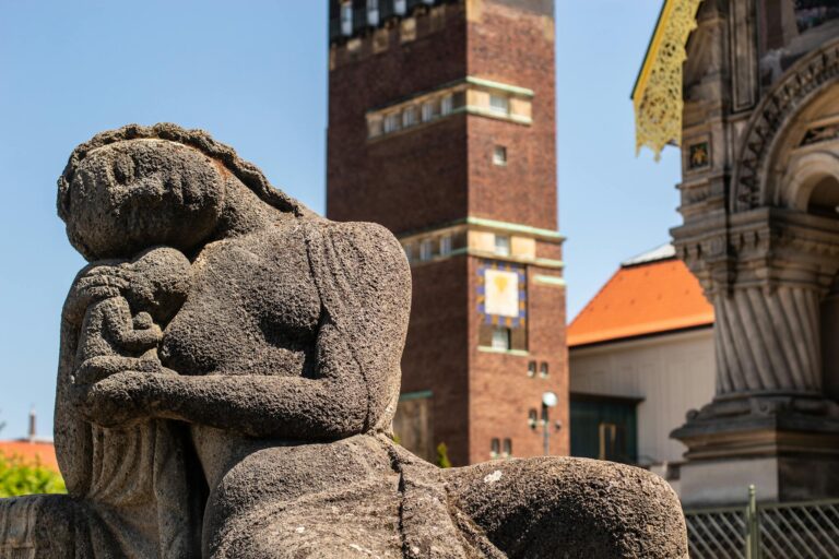 Captivating stone sculpture beside Darmstadt's iconic architecture under clear skies.