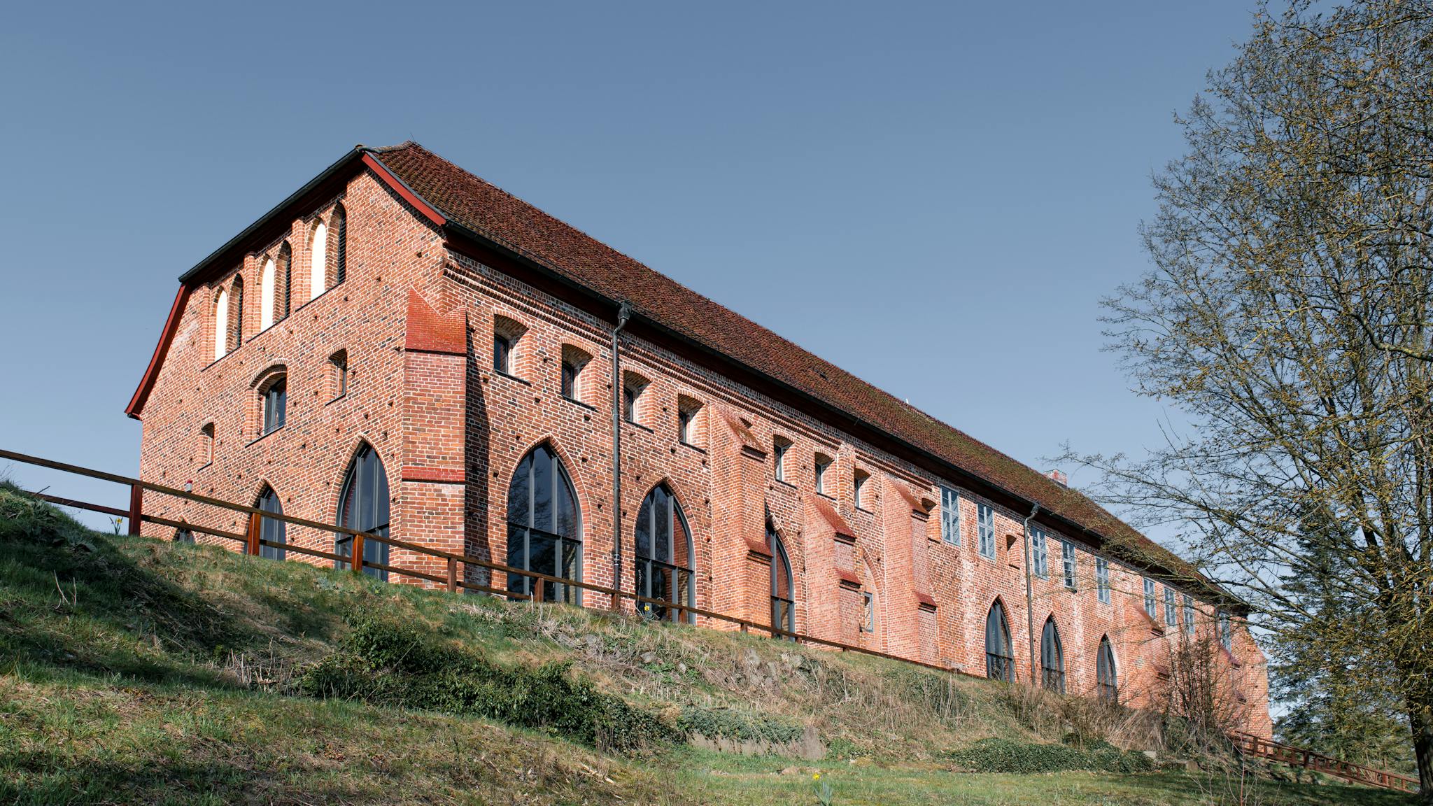 Red brick building in Zarrentin am Schaalsee, showcasing Gothic architectural features. Clear blue sky enhances its charm.